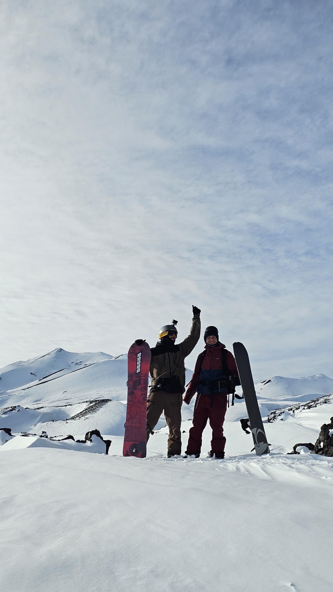 Snowboarders celebrando en la cumbre con sus tablas