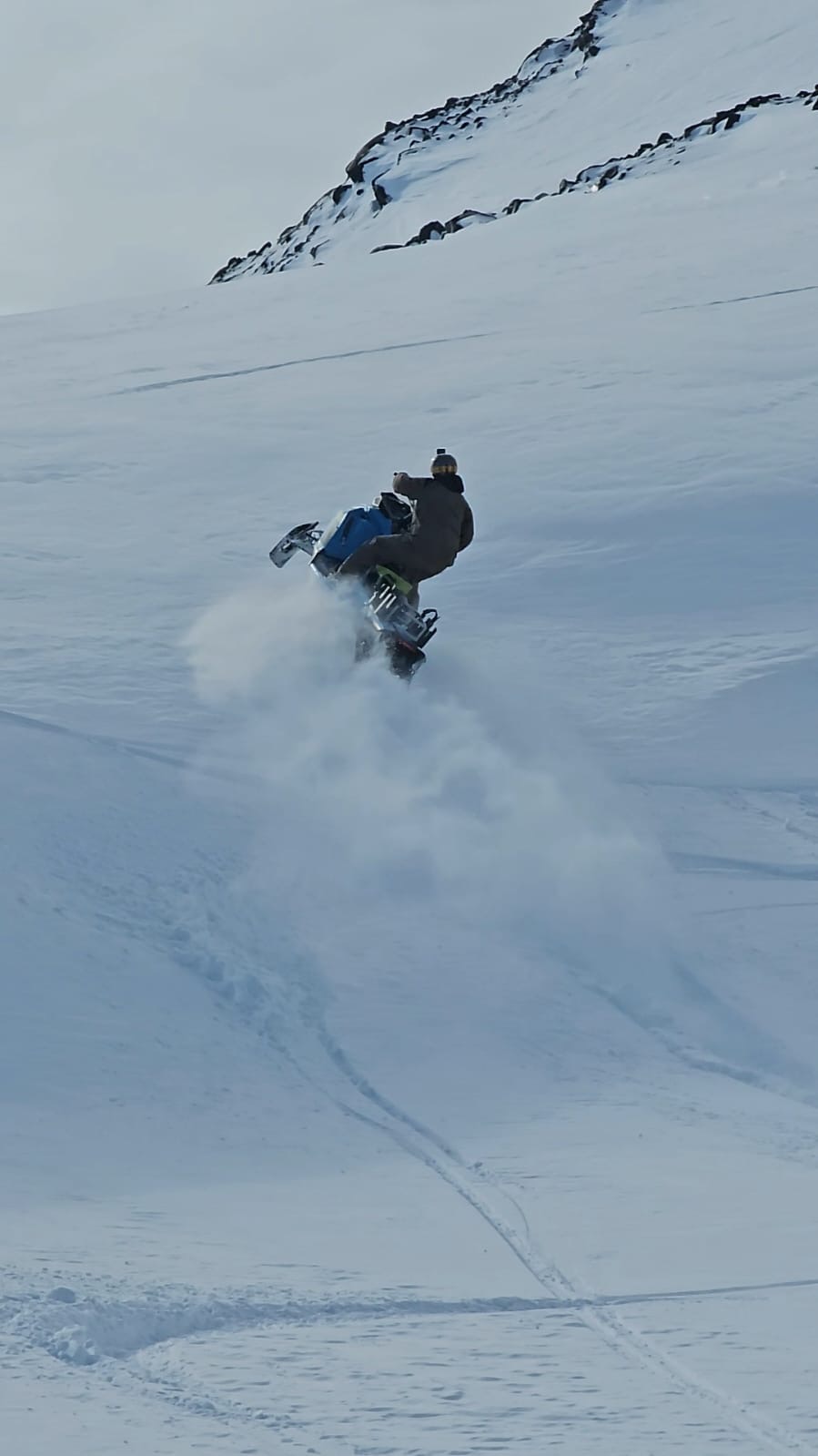 Moto de nieve levantando polvo en plena bajada por la montaña
