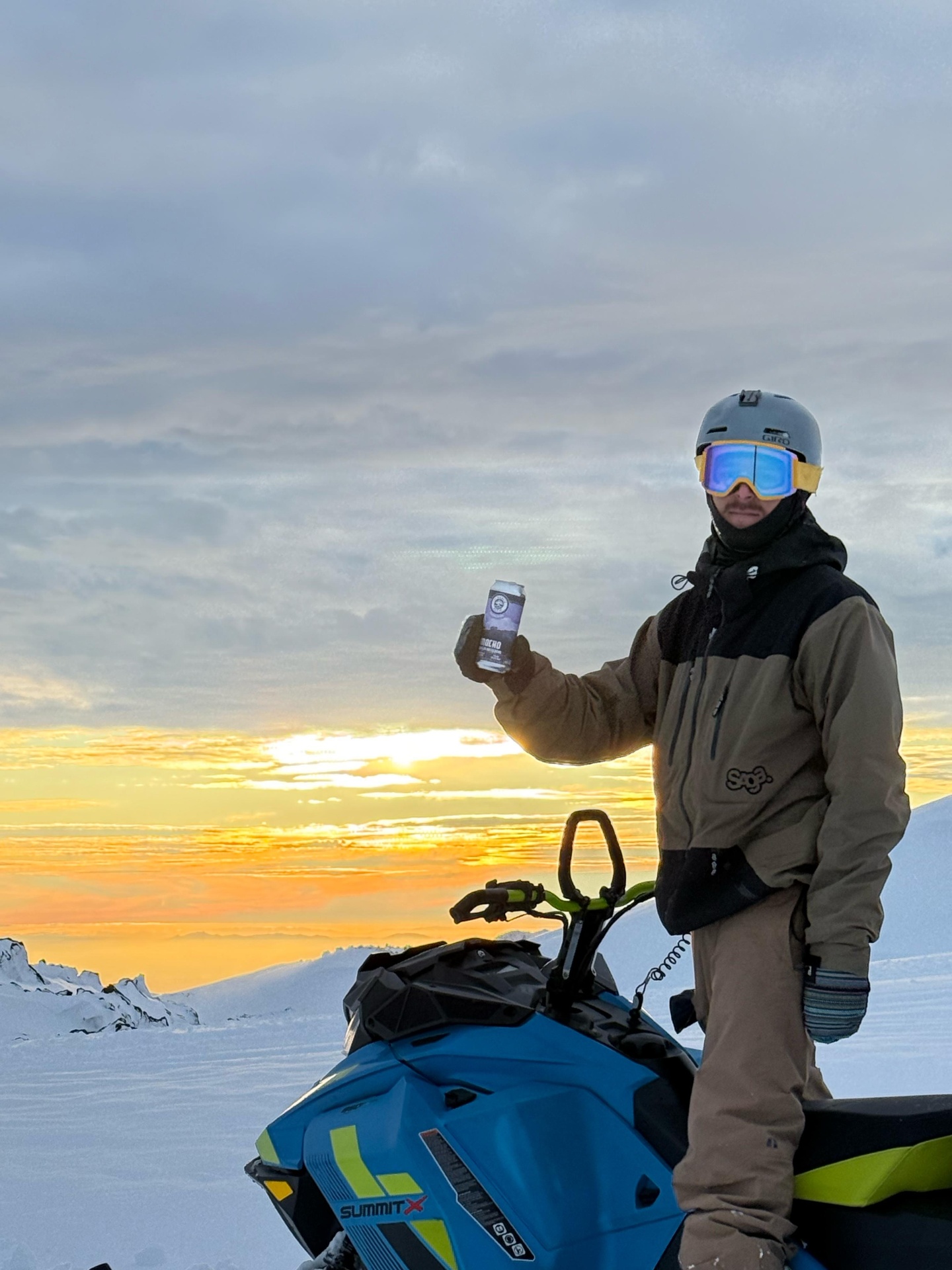 Rider con cerveza junto a su Ski-Doo Summit al atardecer
